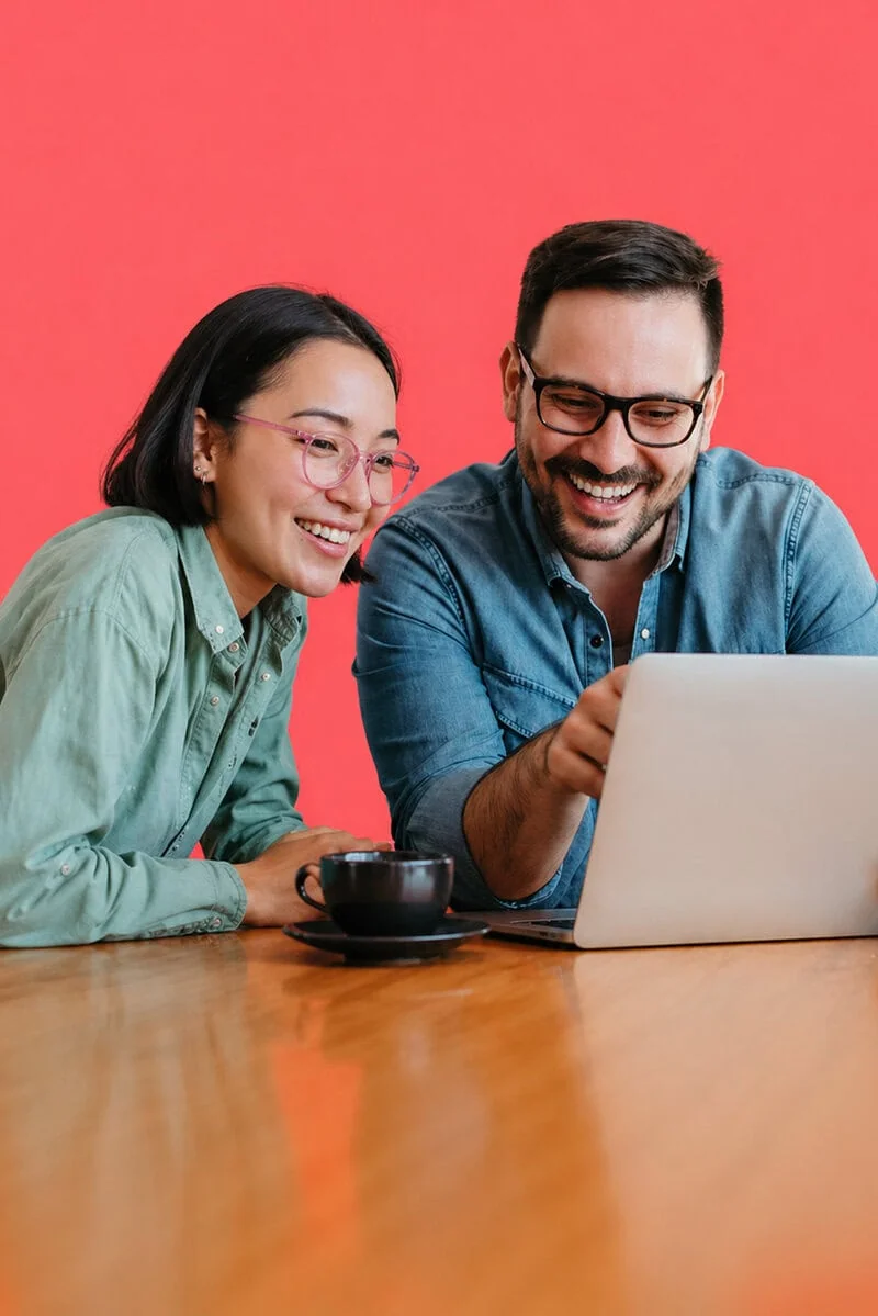 Two people reviewing a design on a laptop, representing graphic design collaboration and brand development