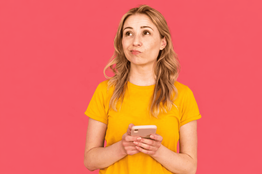 Woman looking confused at her phone on a pink background, representing a website losing customers